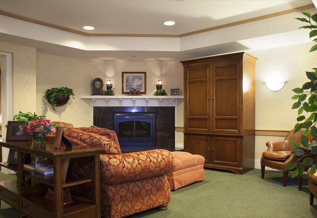 A cozy living room with a fireplace, comfortable seating, and elegant wooden furniture.