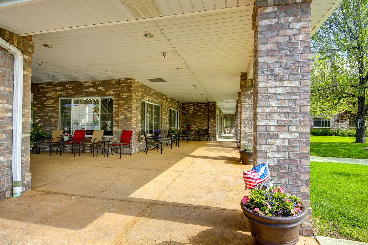 A covered patio area with brick walls, outdoor seating, and a flower pot displaying an American flag.