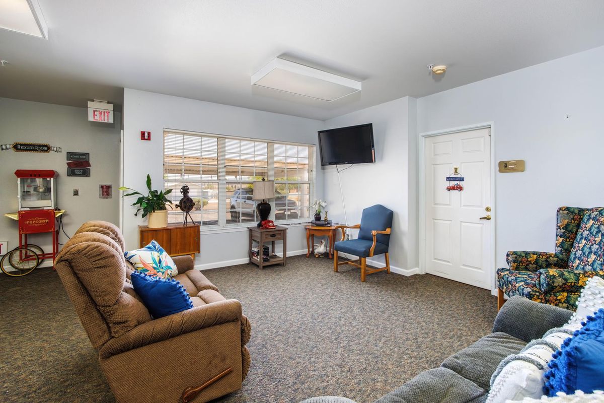 A cozy living room with couches, a chair, and a wall-mounted television.