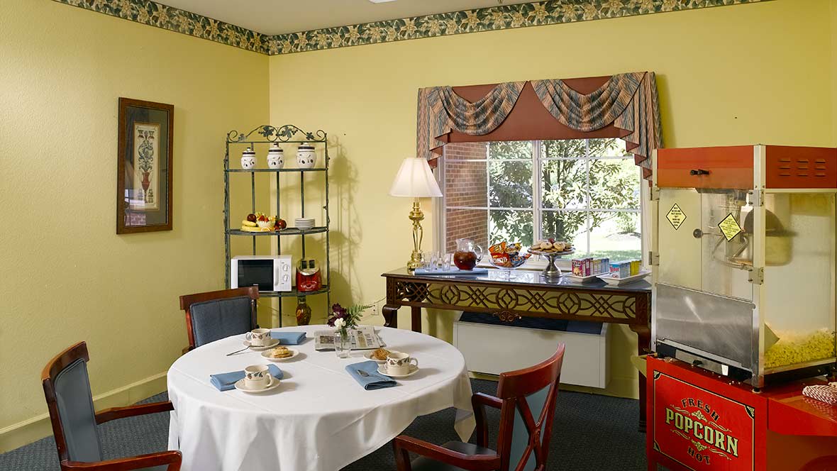 A cozy dining room with a round table set for a meal, featuring warm yellow walls and classic decor.