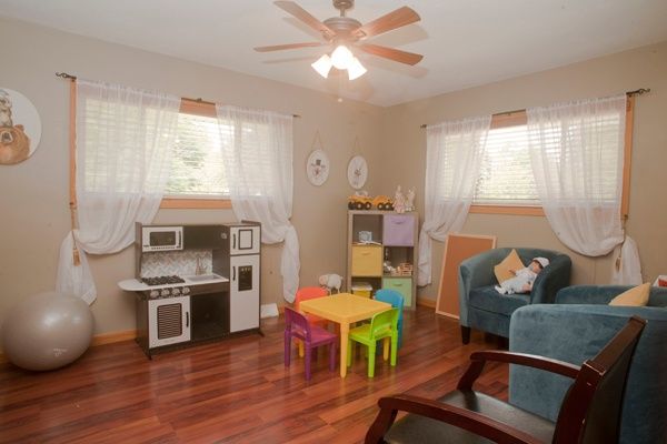 A cozy children's playroom featuring a colorful table and chairs set, a kitchen playset, and toys on display.