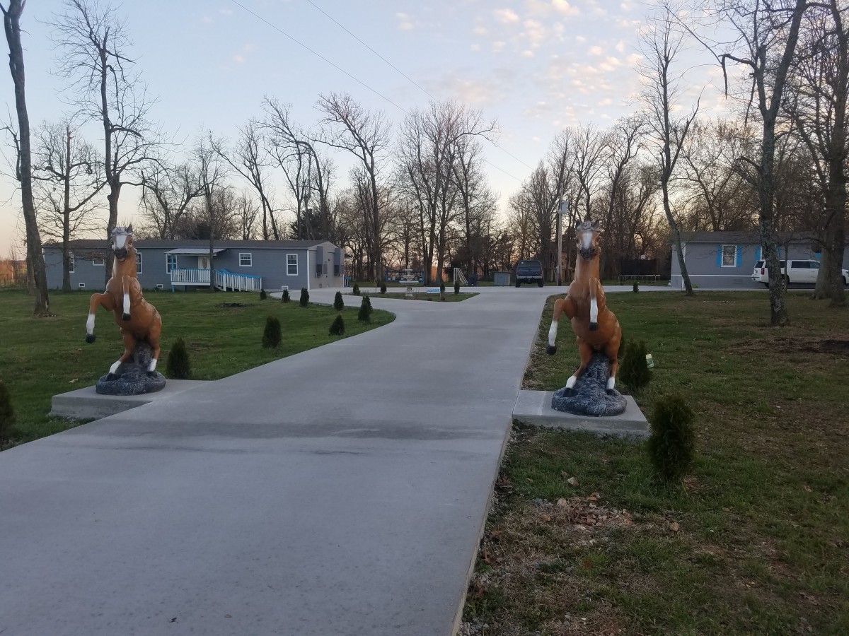 A pathway lined with horse statues in a park setting.