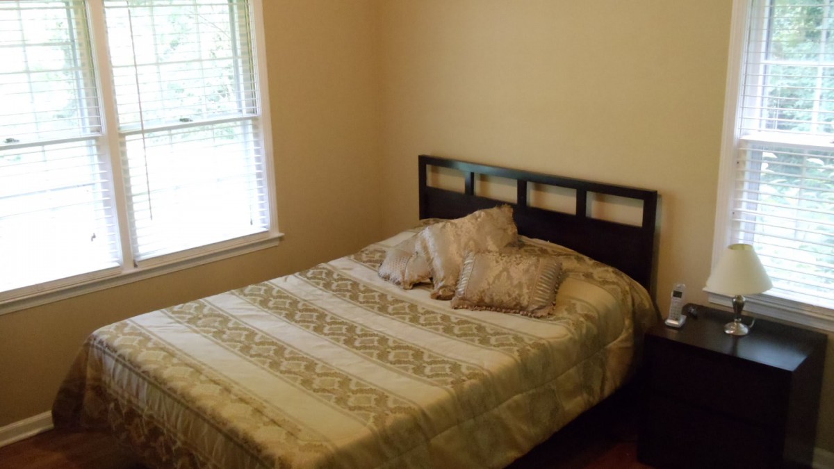 A cozy bedroom with a bed and pillows near a window.