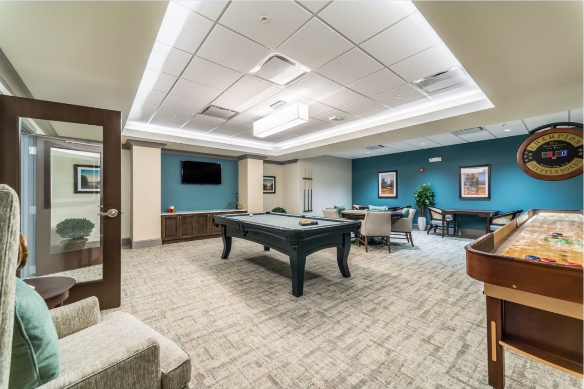 A modern game room featuring a billiards table, seating area, and a television.