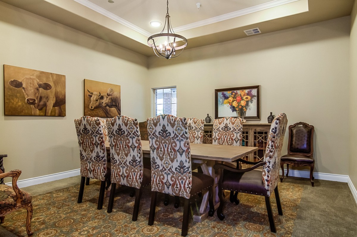A well-decorated dining room with a large table, upholstered chairs, and a chandelier.