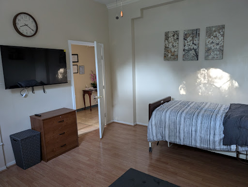 A cozy bedroom featuring a single bed, television, and decorative artwork on the walls.