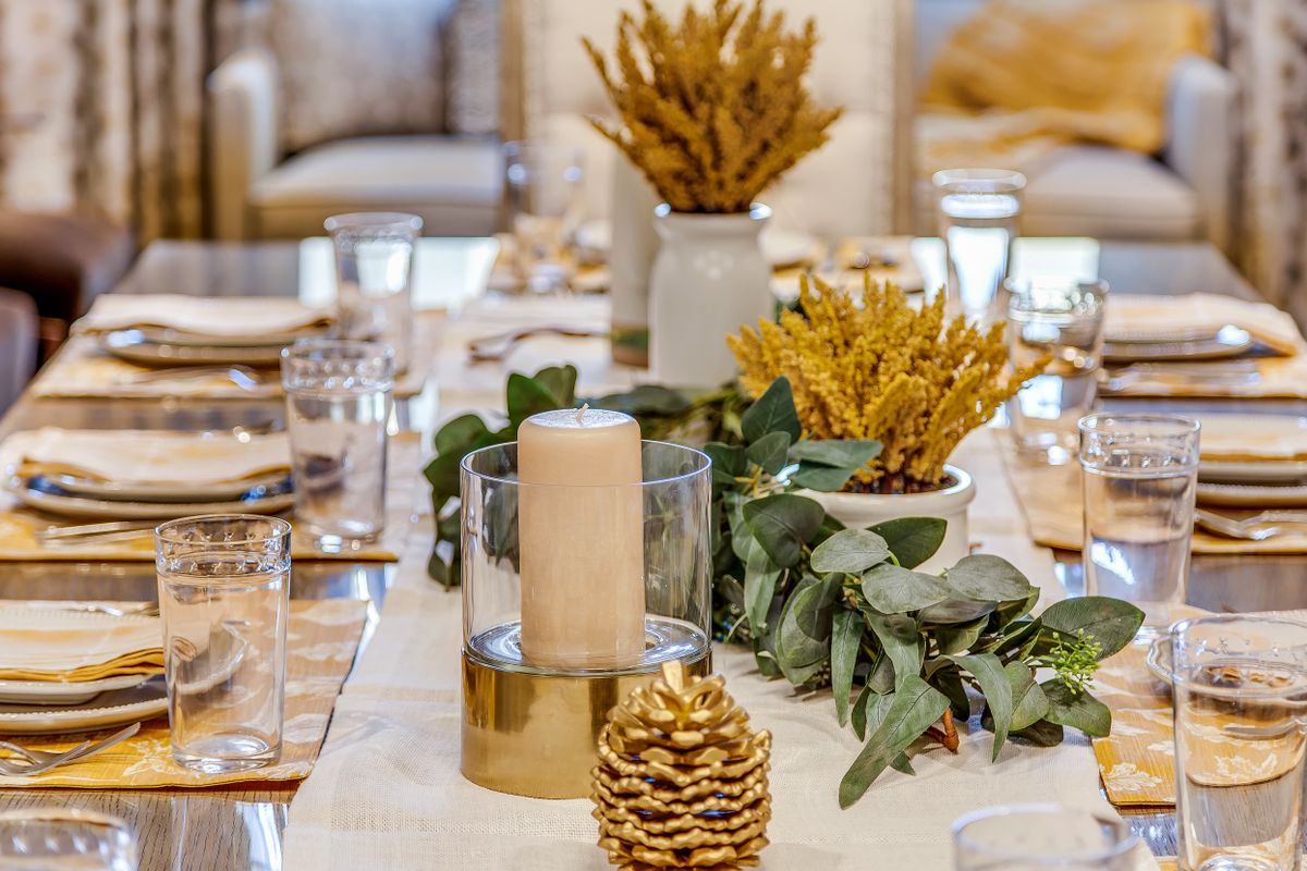 An elegantly decorated dining table with candles and foliage centerpieces.