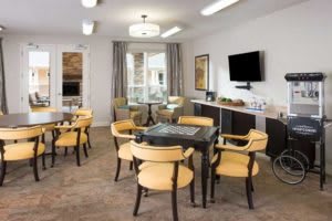 A well-lit meeting room with tables, chairs, and a wall-mounted television.