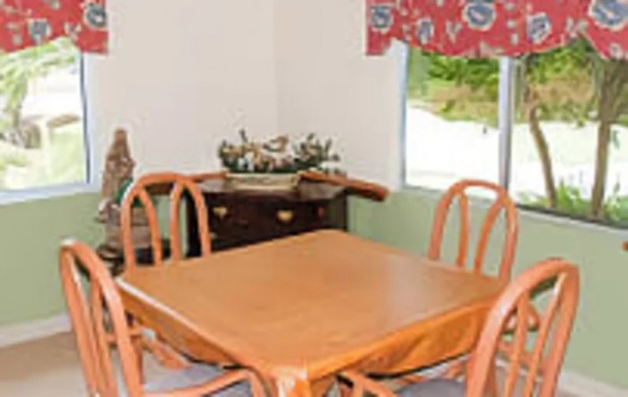 A cozy dining area with a wooden table and chairs next to a window with floral curtains.