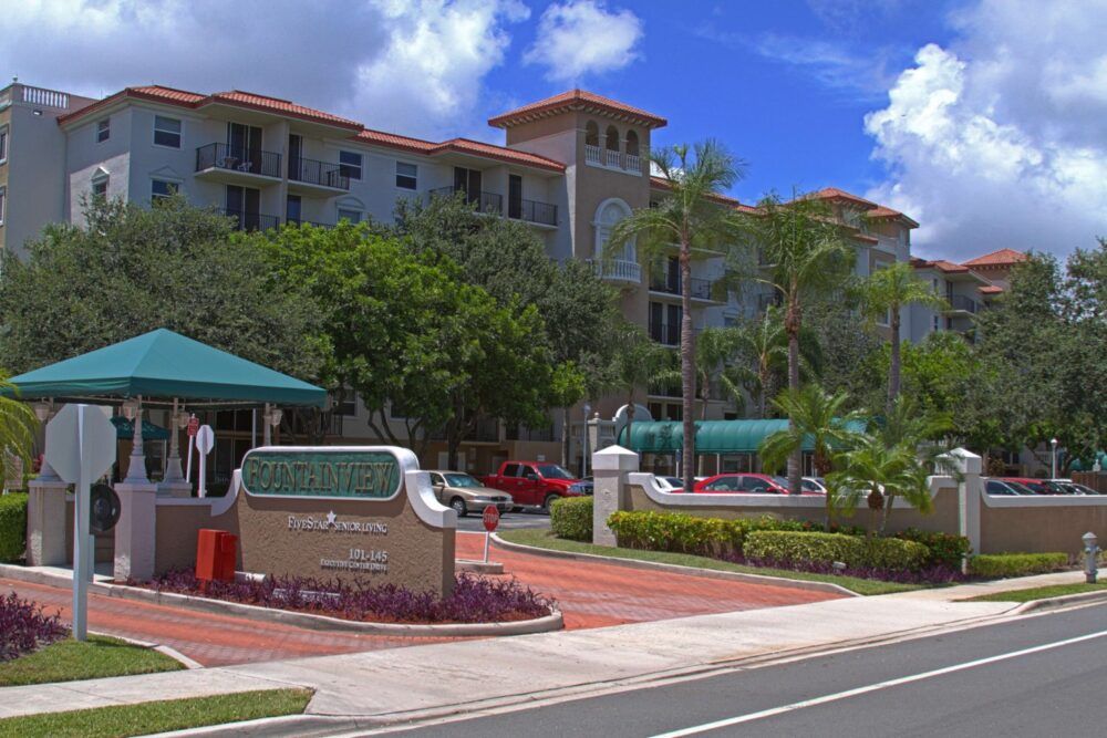A tropical hotel or resort with palm trees lining the street.