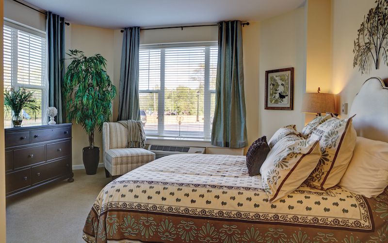 A cozy bedroom with a comfortable bed, large window, and stylish decor.