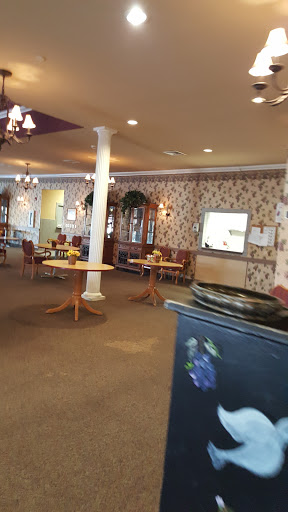 A cozy dining area with floral wallpaper and tables set for guests.