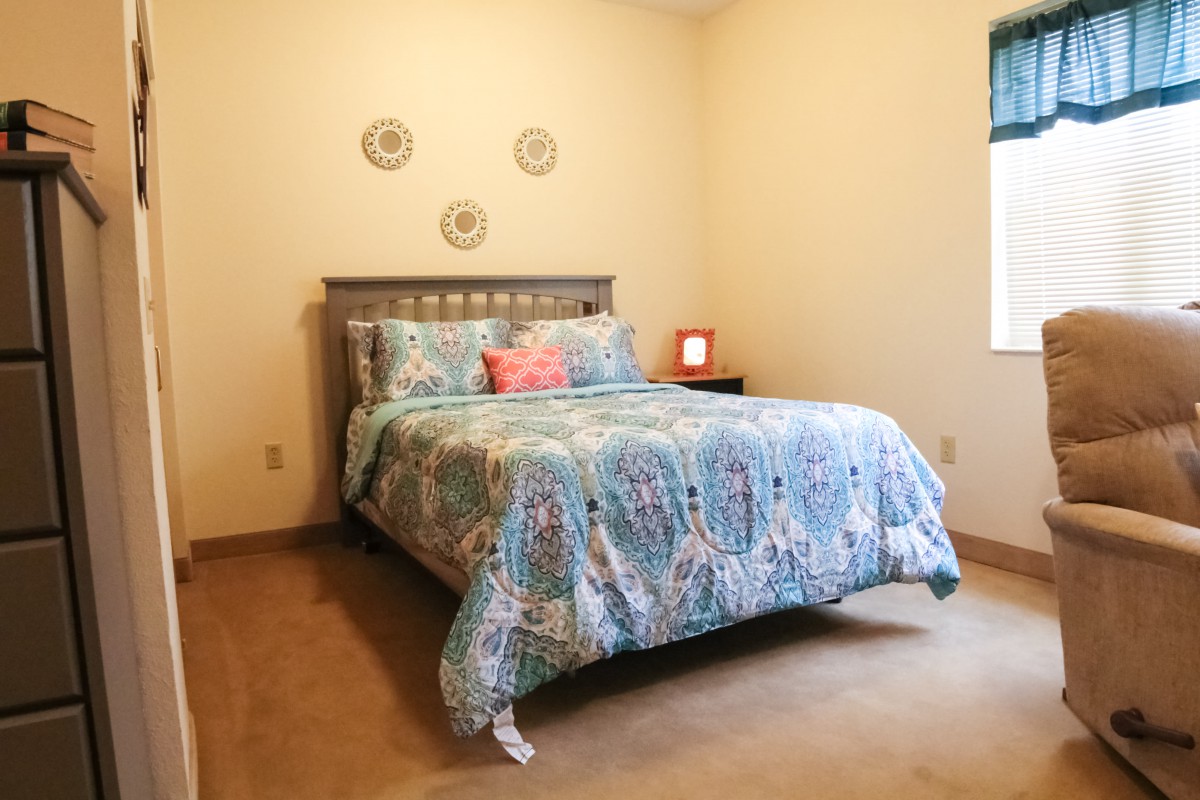 A cozy bedroom with a patterned bedspread and simple decor.