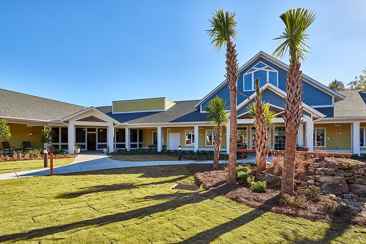A beautiful house with palm trees and well-maintained landscaping under a clear blue sky.