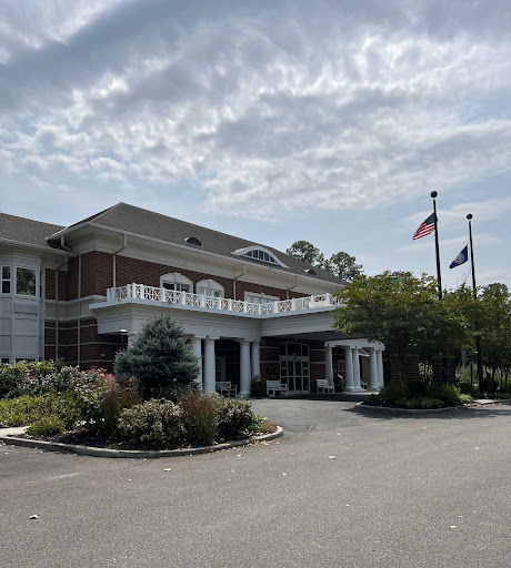 A well-designed building with flags in front under a cloudy sky.