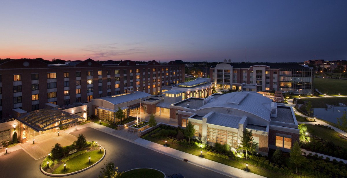 A modern hotel building illuminated at night with landscaped surroundings.