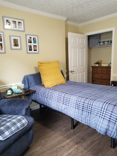 A cozy and neatly arranged bedroom featuring a single bed with plaid bedding and a yellow accent pillow.