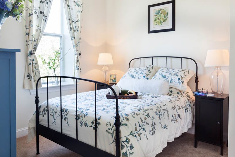 A cozy bedroom with floral bedding and a decorative lamp by the window.