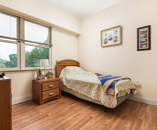 A cozy bedroom with a single bed, nightstand, and framed pictures on the wall.