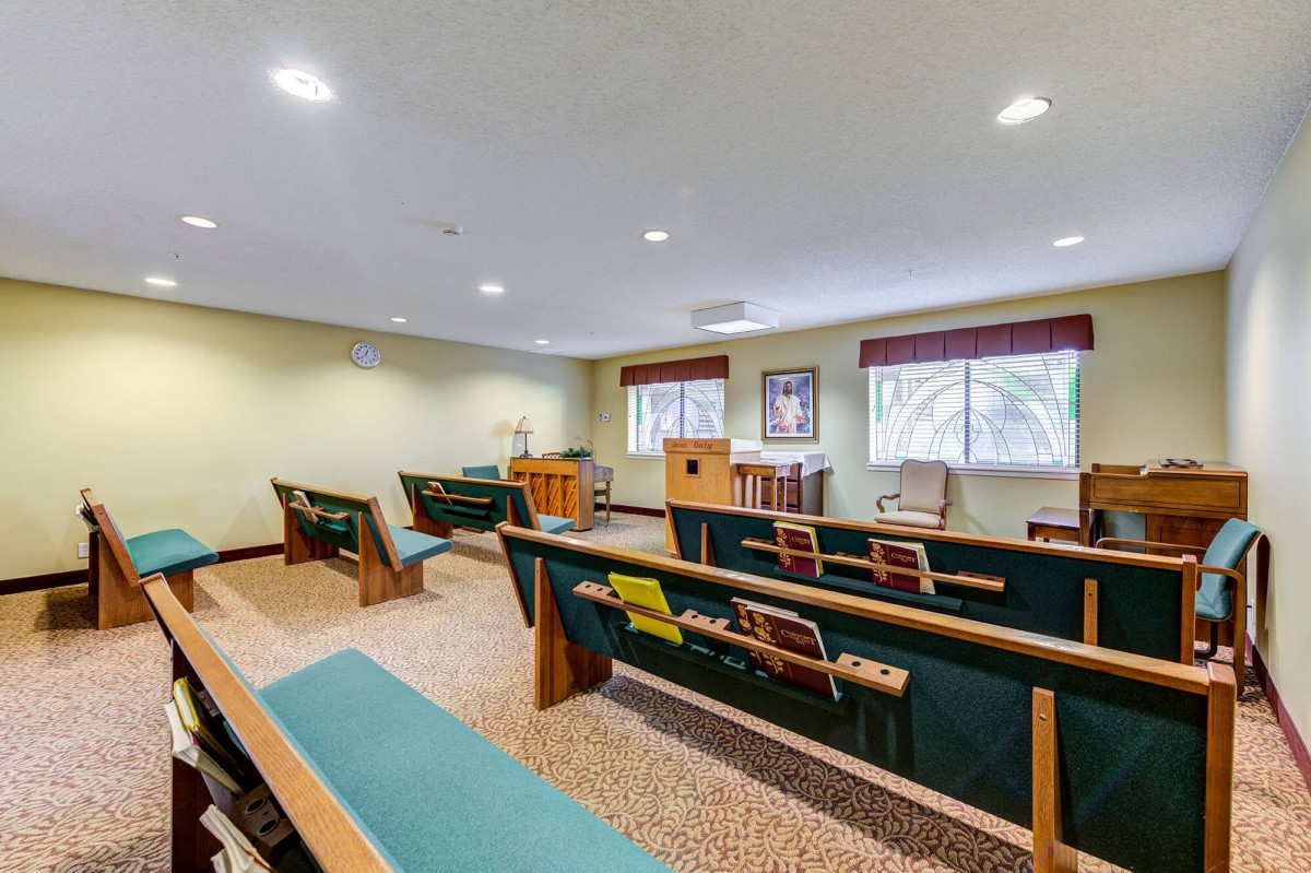 An interior view of a chapel with rows of pews and a pulpit at the front.