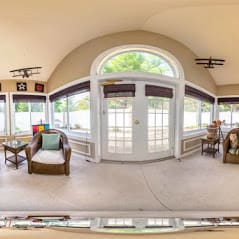 A bright and spacious sunroom featuring cozy furniture and large windows.