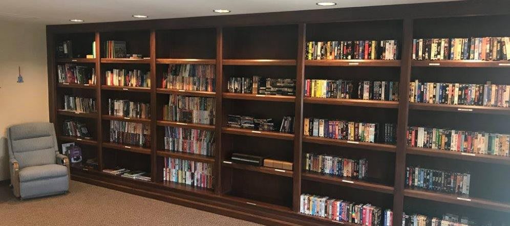 A spacious wooden bookshelf filled with a variety of books and media.