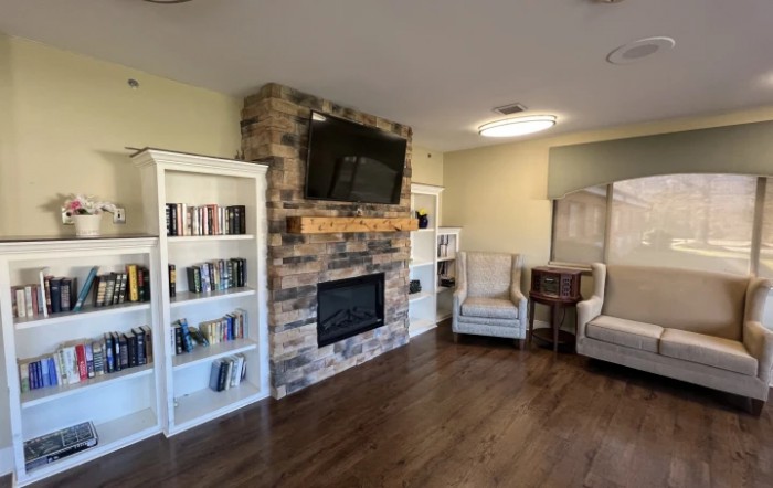 A cozy living room with a fireplace, bookshelves filled with books, and comfortable seating.