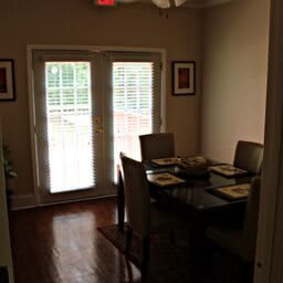 A cozy dining room with a set dining table and French doors leading outside.