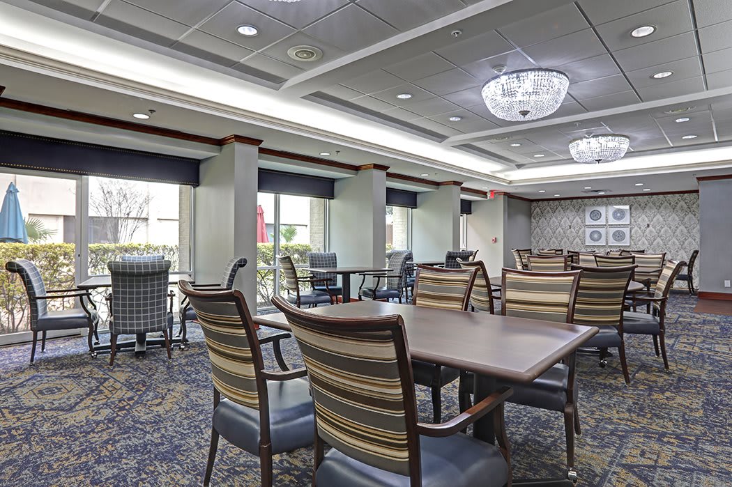 A spacious dining area with tables and chairs, featuring large windows and elegant lighting.