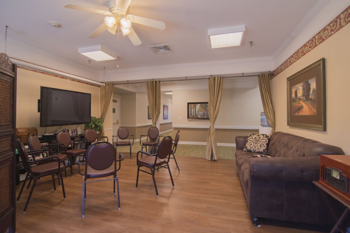A cozy living room with seating area, featuring a couch, chairs, a table, and a television.