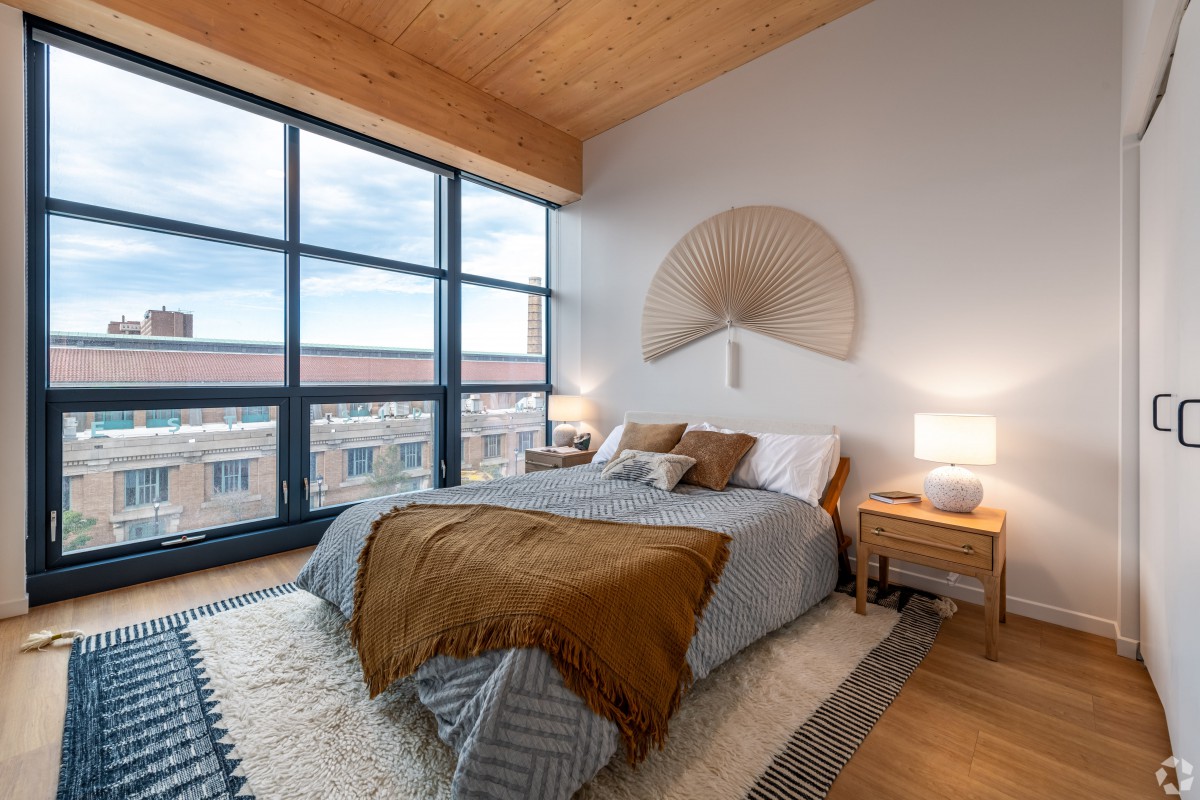 A modern bedroom with large windows, natural light, and stylish decor.