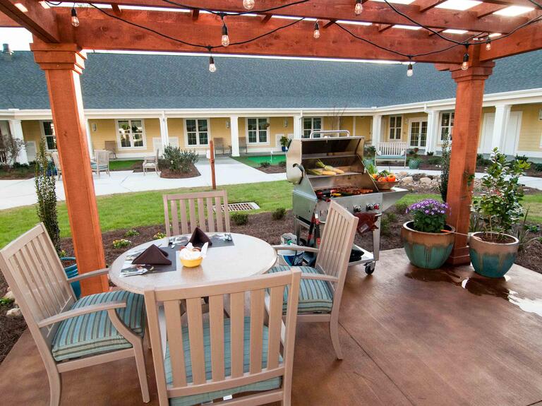 A cozy outdoor patio area with a pergola, featuring seating and a garden view.