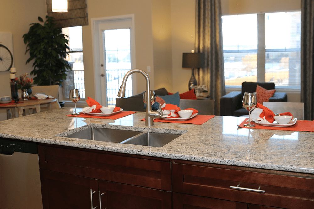 A modern kitchen with a granite countertop and elegant place settings.