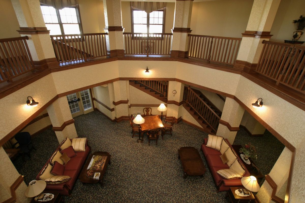 A spacious two-story living room with a central table, surrounded by sofas and an upper balcony.