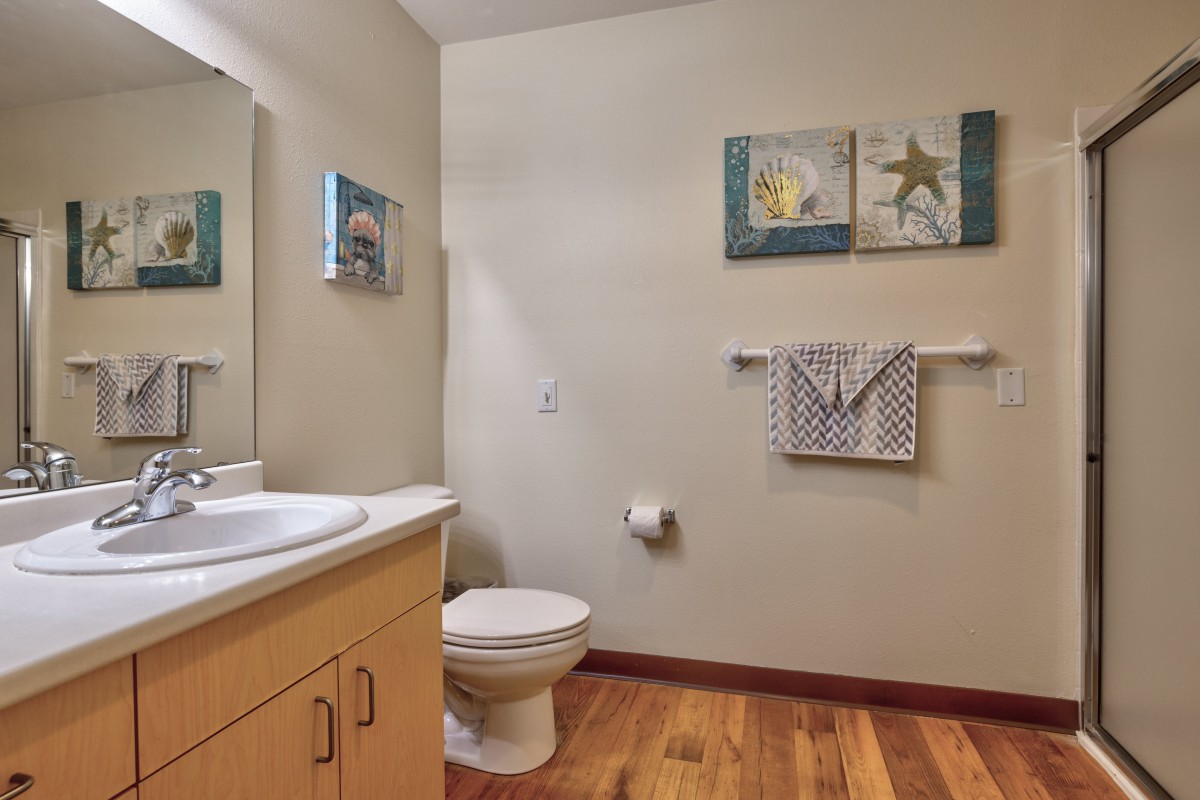 A clean and neatly organized bathroom featuring a sink, toilet, and decorative wall art.