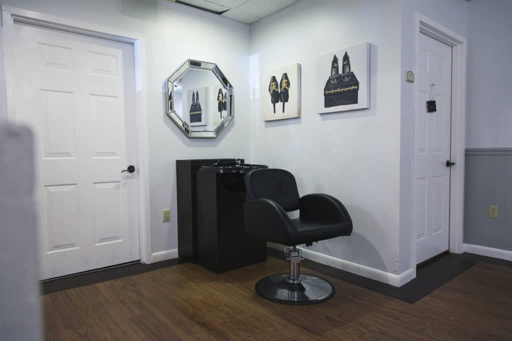A modern salon interior with a stylist chair, mirror, and artwork on the walls.