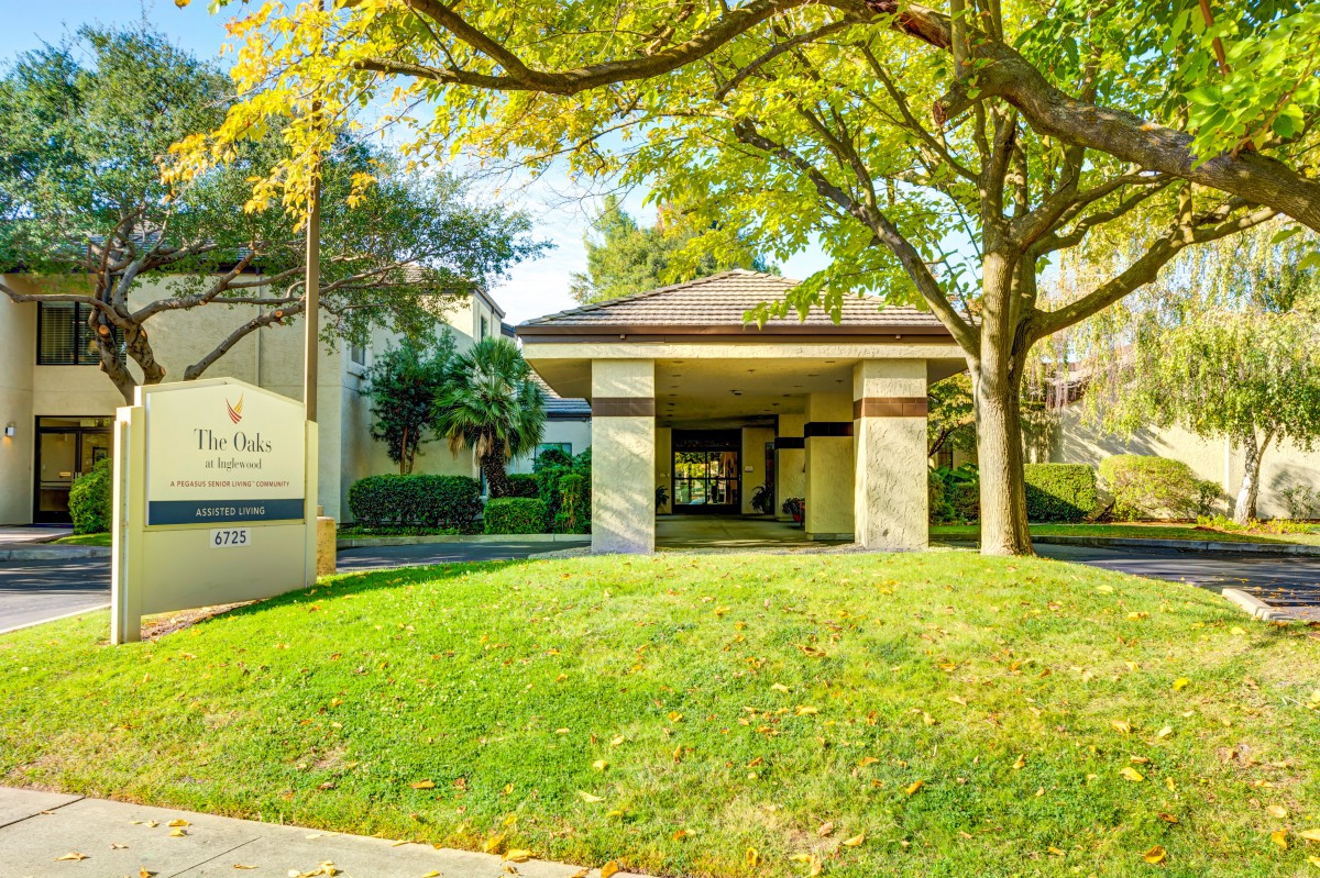 A building entrance surrounded by lush greenery and a well-maintained lawn.