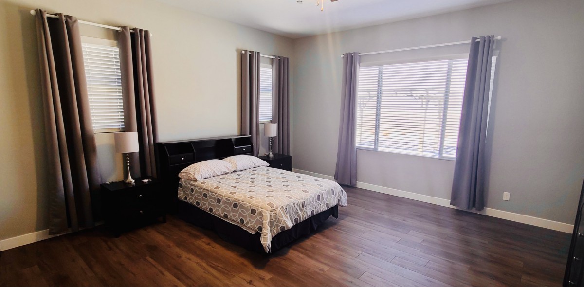 A simple bedroom with a bed, nightstand, and ample natural light.