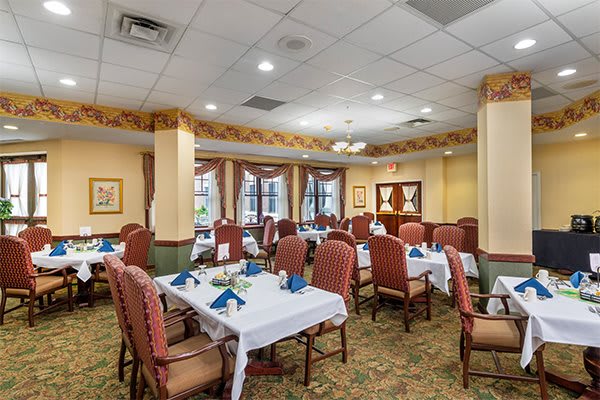 A well-decorated dining room with elegantly set tables and upholstered chairs.