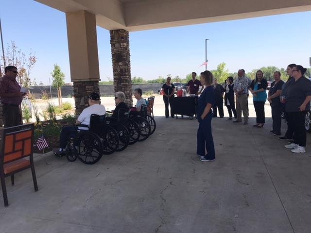 A group of people, including individuals in wheelchairs, participate in an outdoor gathering under a covered area.
