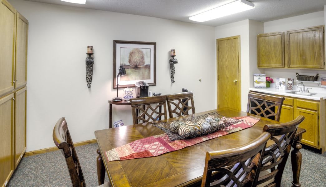 A well-furnished conference room with a long wooden table, chairs, and decorative artwork on the walls.