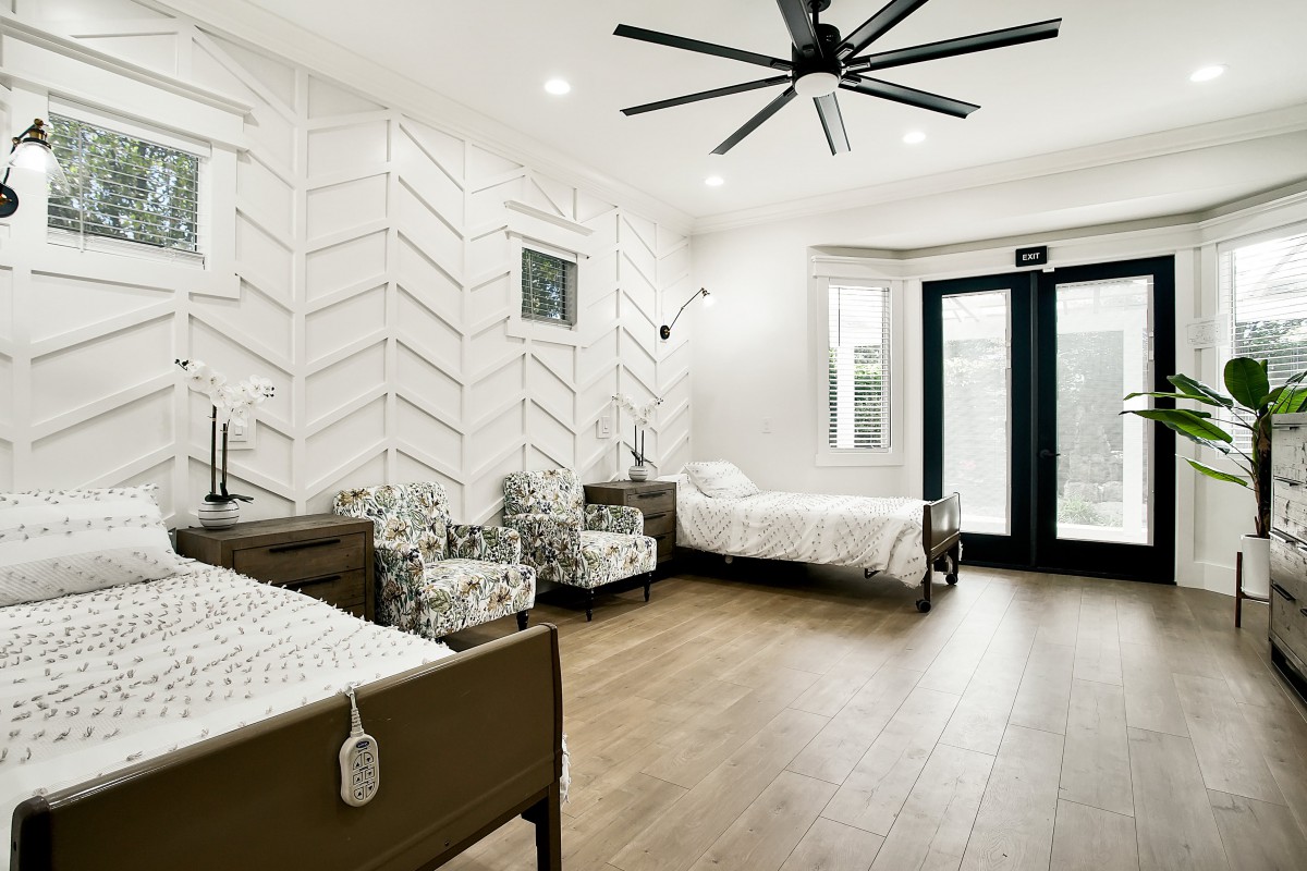 A modern bedroom featuring twin beds, a chevron-pattern accent wall, and sleek wood flooring.