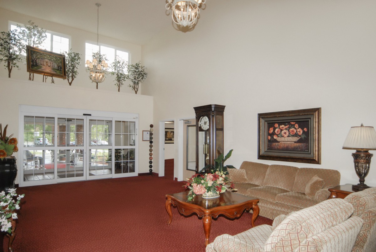 A spacious lobby with elegant chandeliers, comfortable seating, and classic decor including a grandfather clock.