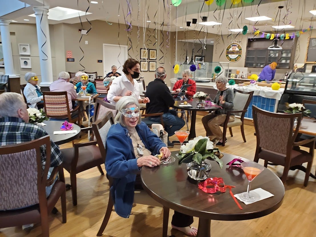 A lively indoor party with decorations as elderly guests enjoy the celebration.