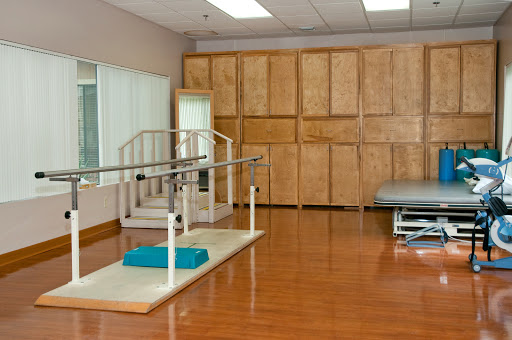 A spacious physical therapy room equipped with parallel bars and exercise mats for rehabilitation.
