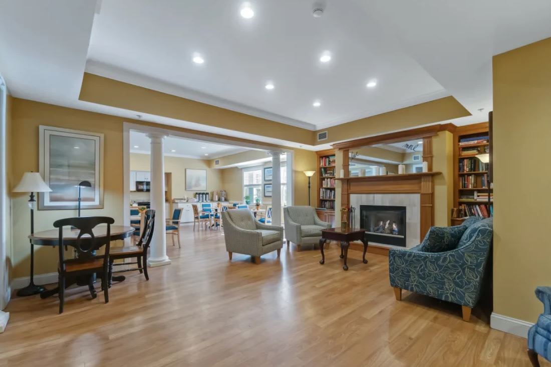A spacious living room with elegant furniture and a cozy fireplace, featuring hardwood floors and warm lighting.