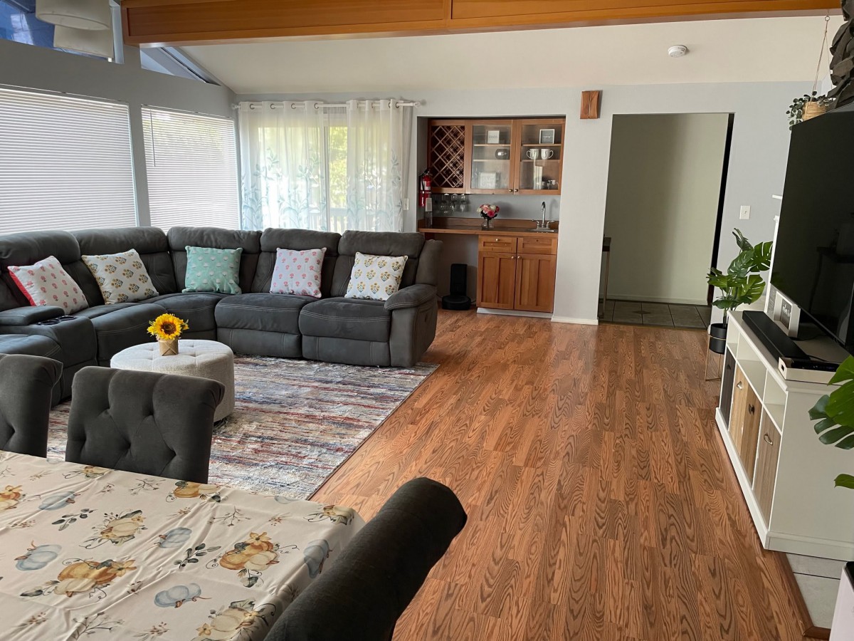 A cozy living room with a large sectional sofa, wooden floors, and a well-decorated interior.