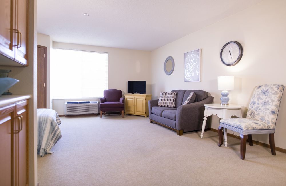 A cozy living room with a sofa, chair, and television.