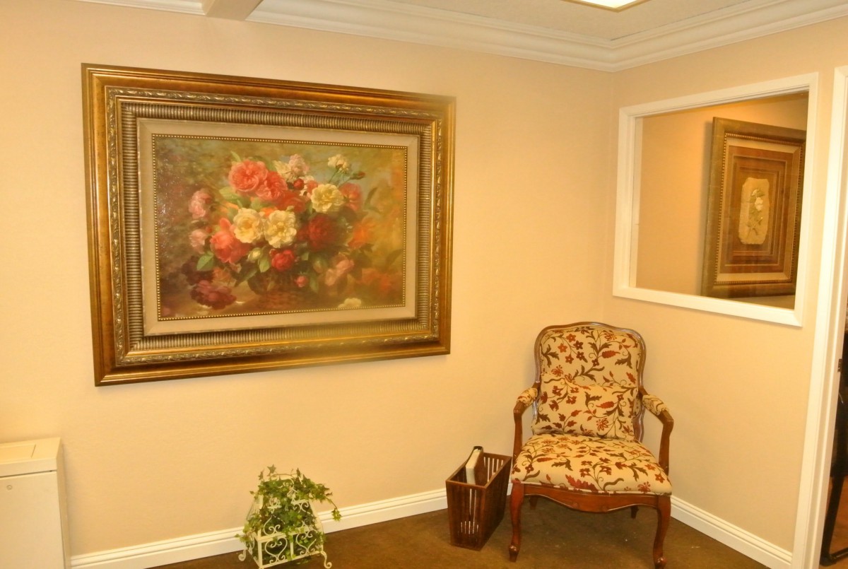 A cozy room with a floral painting and an ornate chair.