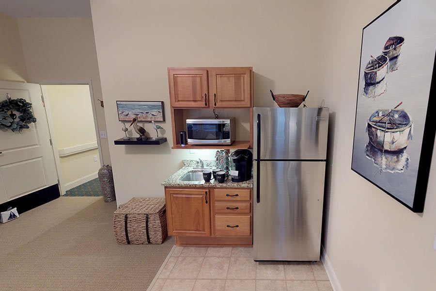 A small kitchen area with a mini-fridge, microwave, and wooden cabinets.